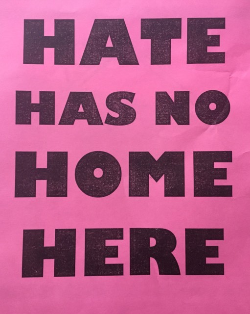 Pink background, black text reading "Hate Has No Home Here"