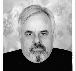 Black and white photo of a masculine looking person with a beard staring directly into the camera.