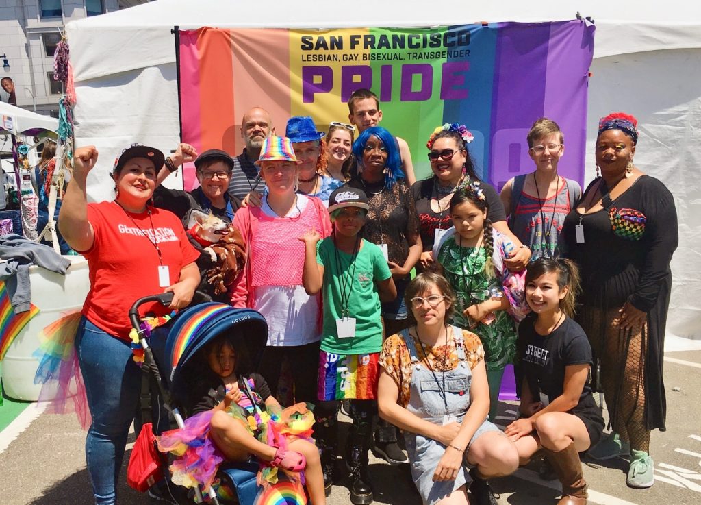 A crew from the Coalition on Homelessness in front of a rainbow backdrop reading San francisco Lesbian, Gay, Bisexual, Transgender Pride