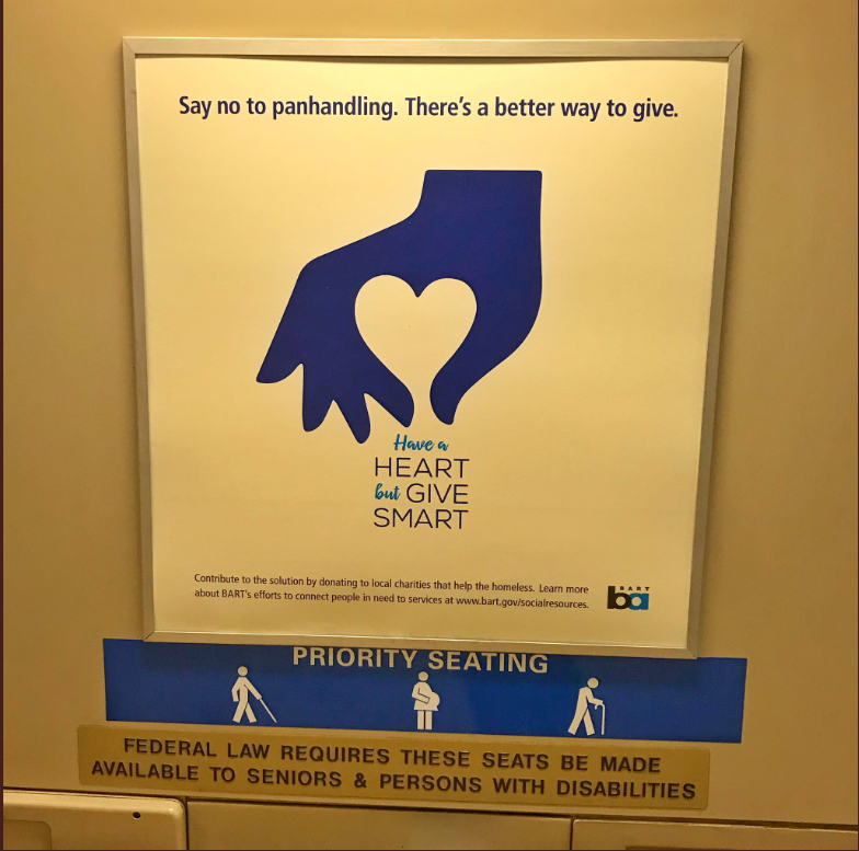 BART advertisement reads “Say no to panhandling. There’s a better way to give.” with a hand forming a heart around words reading “Have a HEART but GIVE SMART”