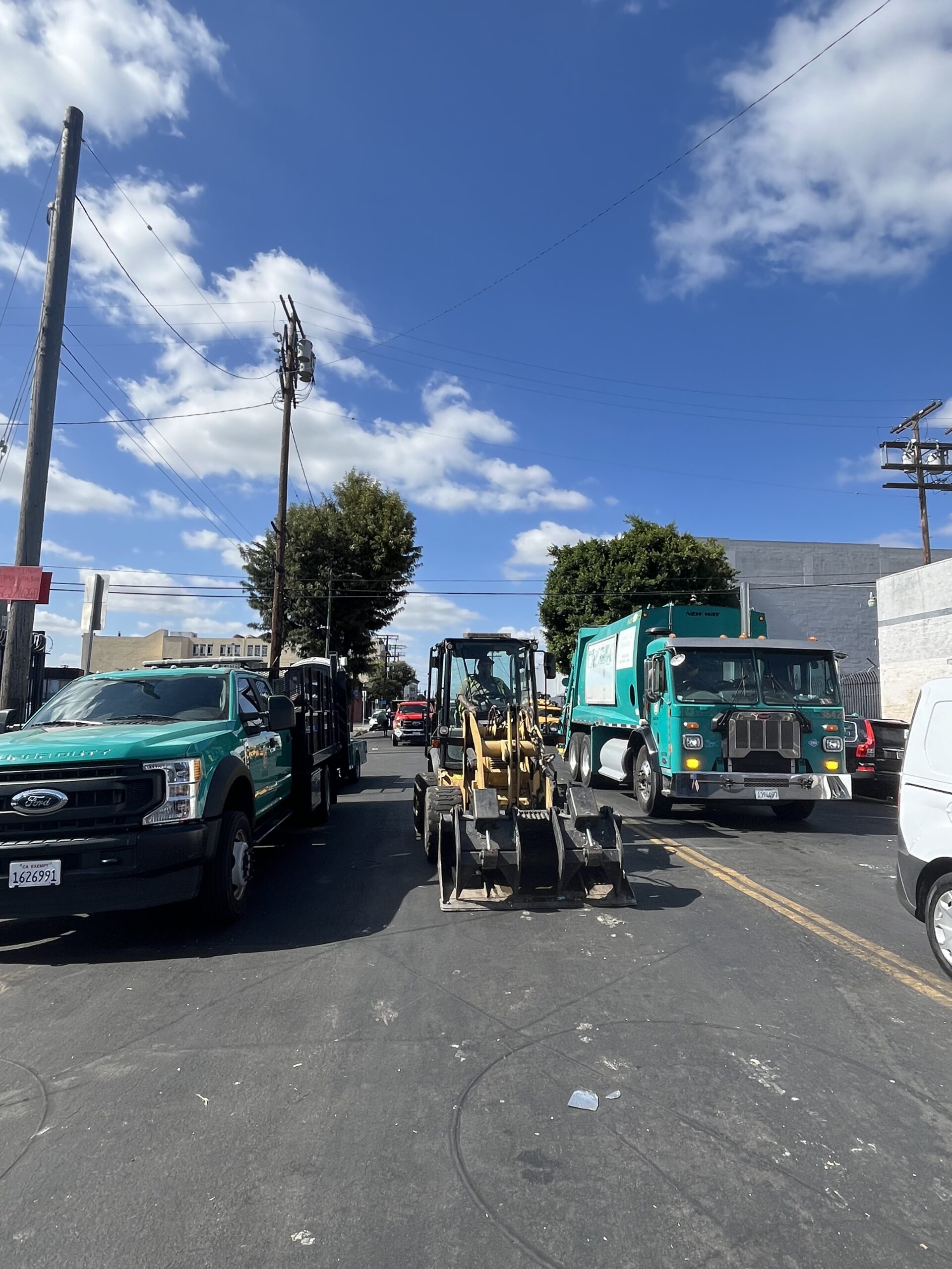 Trucks and bulldozers are prepared for sweeping a homeless encampment on a street in Los Angeles.